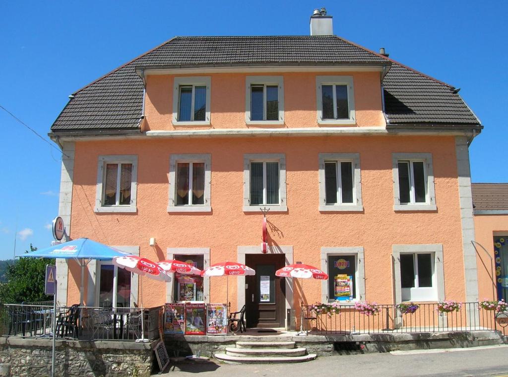 un grande edificio arancione con ombrelloni di fronte di Chambres d'Hotes Le Passiflore a Les Brenets