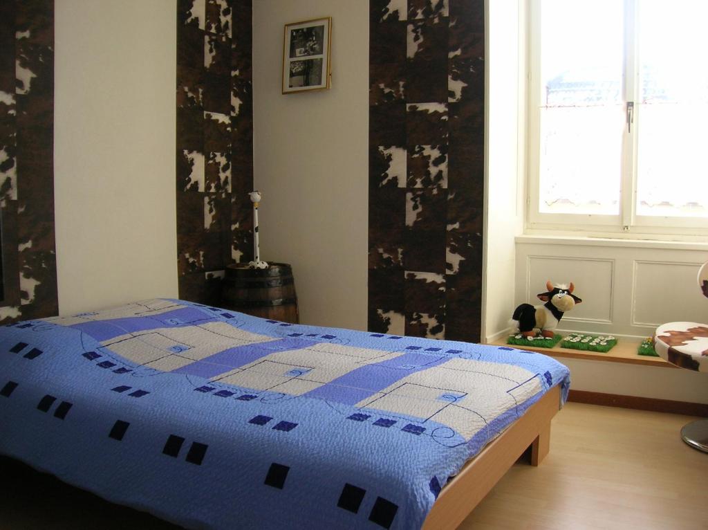 a bedroom with a bed with a blue quilt on it at Chambres d'Hotes Le Passiflore in Les Brenets
