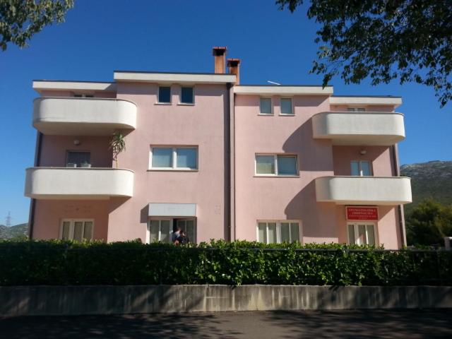 a pink building with white balconies on top of it at Apartment Smodlaka in Dugopolje
