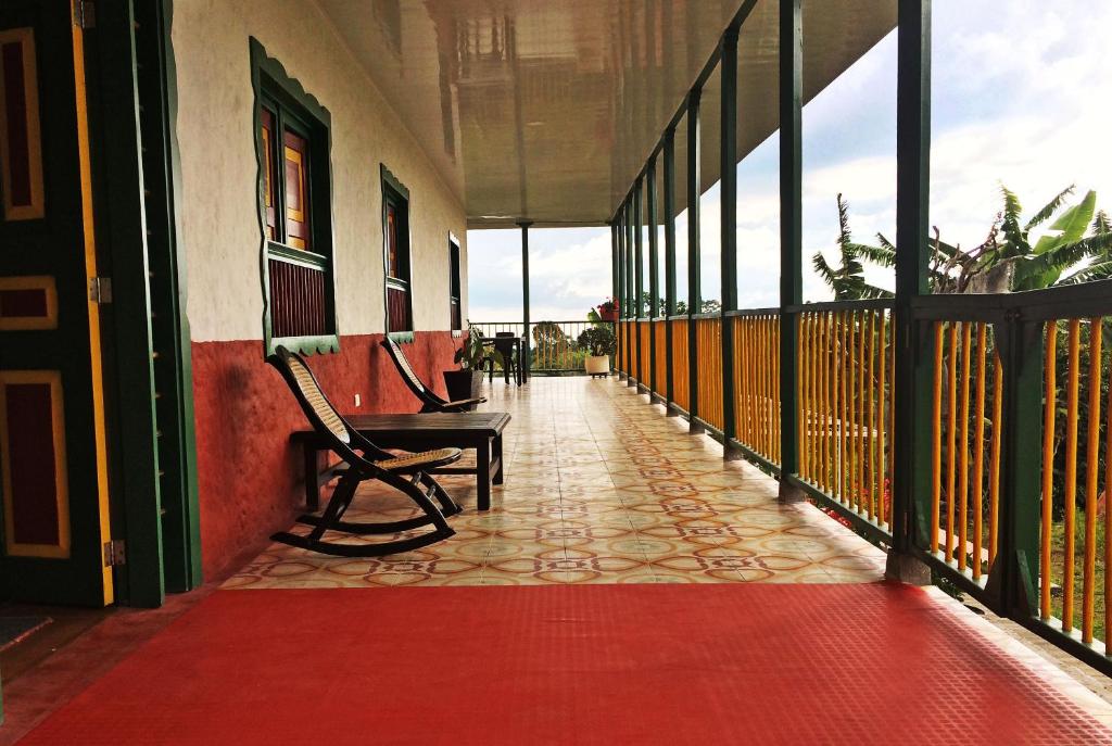 a balcony with a bench and a red floor at Hostal Casa de Los Taitas in Salento