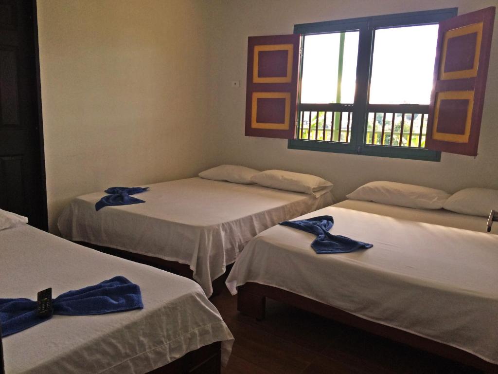 a room with three beds with blue bows on them at Hostal Casa de Los Taitas in Salento