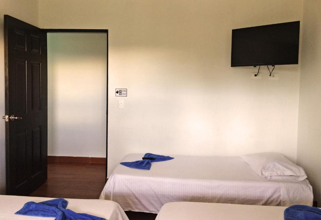 a room with two beds and a flat screen tv at Hostal Casa de Los Taitas in Salento