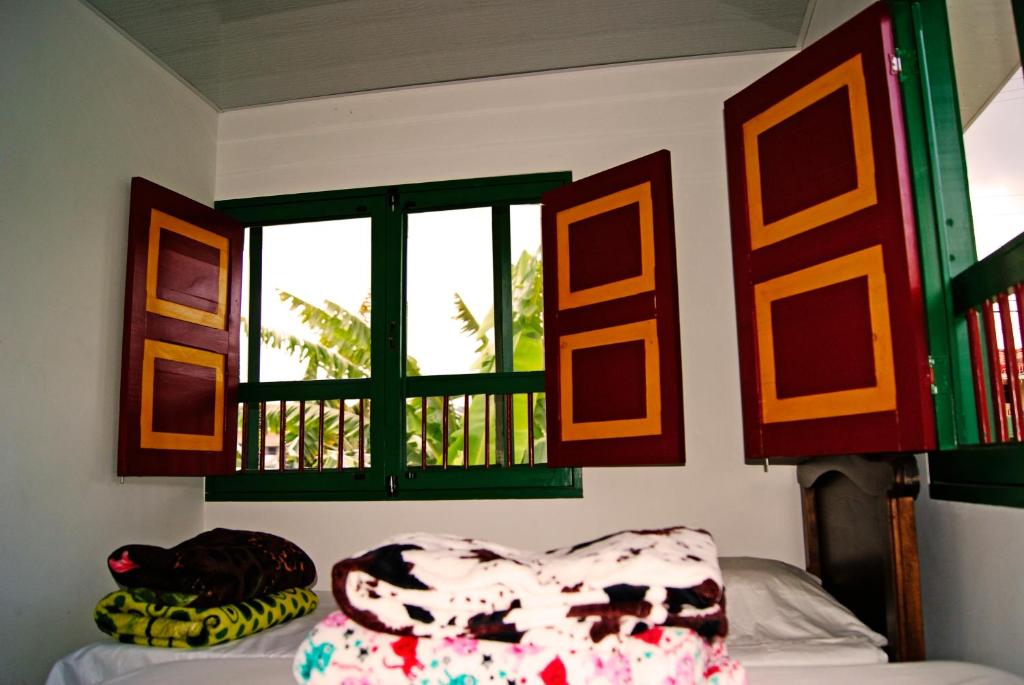 a room with a bed and a window and a chair at Hostal Casa de Los Taitas in Salento