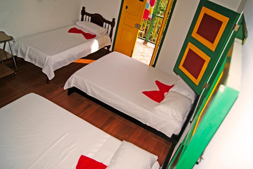 two beds in a room with red and white sheets at Hostal Casa de Los Taitas in Salento