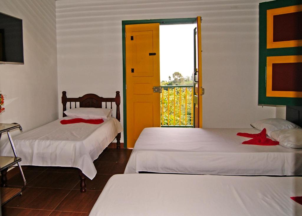 a room with two beds and a door with a window at Hostal Casa de Los Taitas in Salento