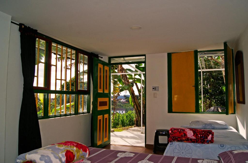 a bedroom with two beds and an open door at Hostal Casa de Los Taitas in Salento