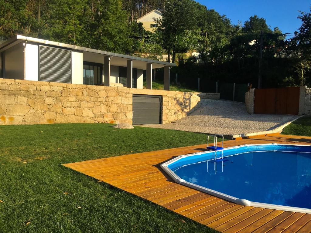 a swimming pool on a wooden deck next to a house at The Green Roof House in Vieira do Minho