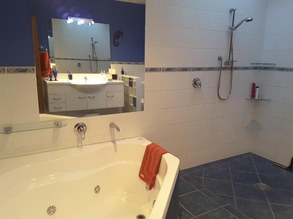 a bathroom with a tub and a sink and a mirror at Beach B&B in Waihi Beach