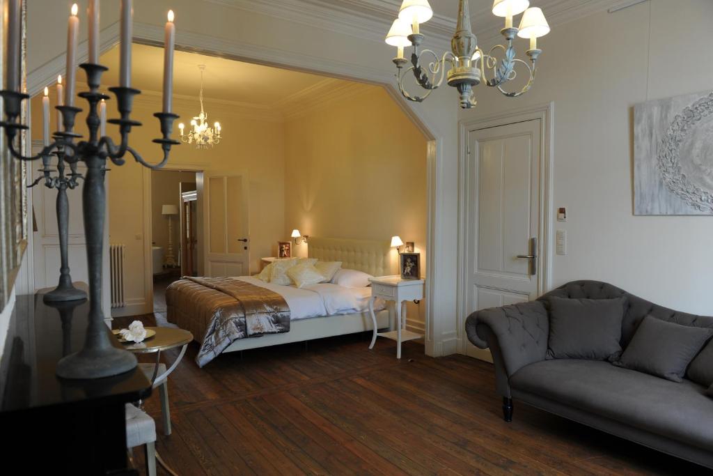 a bedroom with a bed and a couch and a chandelier at Charmehotel Villa Saporis in Hasselt
