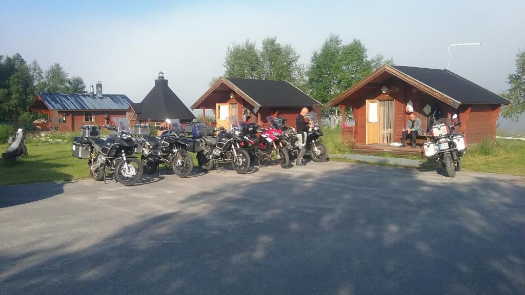 un grupo de motocicletas estacionadas frente a una cabaña en Tenon Eräkievari mökit, en Karigasniemi