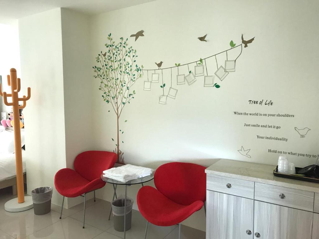 a room with two red chairs and a tree with birds at Yin Mama Warm House in Yilan City