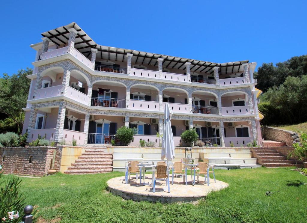 a large white building with chairs in front of it at Residence La Scala in Parga