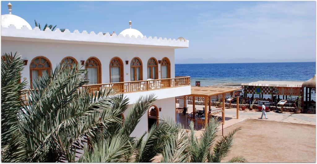 a building on the beach with the ocean in the background at Shams Hotel & Dive Centre in Dahab