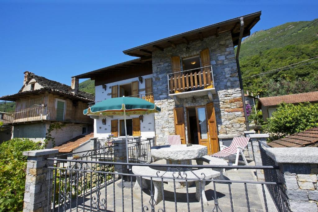 a house with a patio with a table and an umbrella at Rustico Ponte in Cannero Riviera