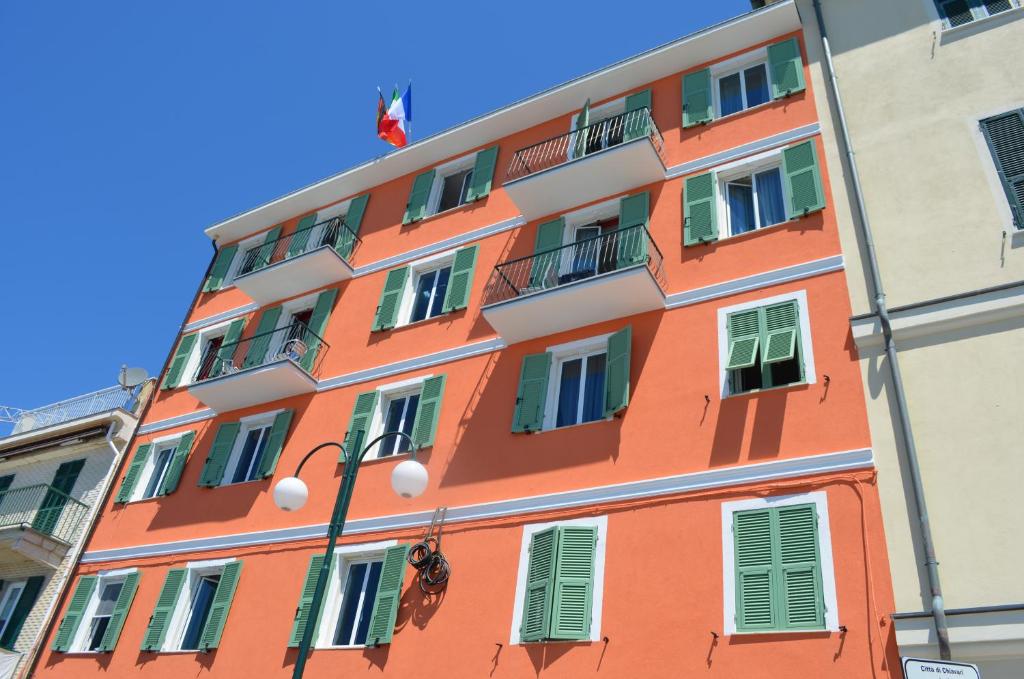 un bâtiment orange avec des fenêtres vertes et un drapeau dans l'établissement Hotel San Pietro Chiavari, à Chiavari