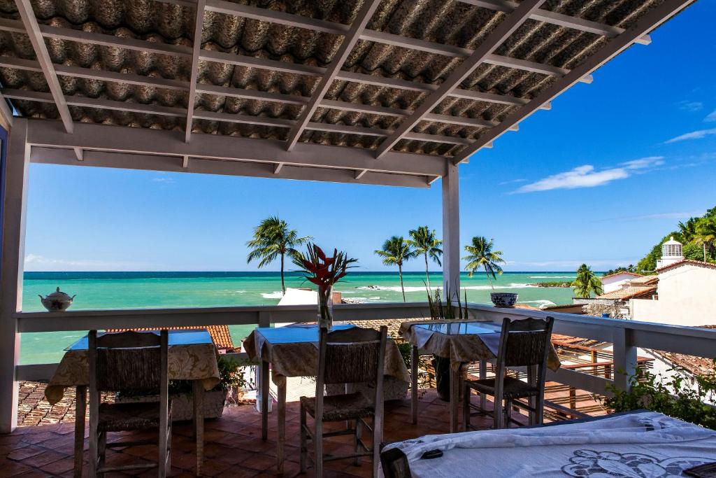 a patio with tables and chairs and the ocean at Pousada Via Brasil in Morro de São Paulo