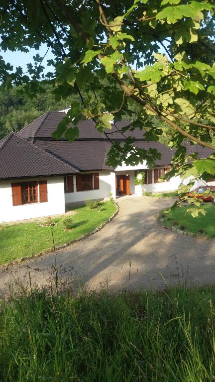 ein weißes Haus mit einem schwarzen Dach und einer Auffahrt in der Unterkunft Ropki Dwór RAJDANY in Ropki