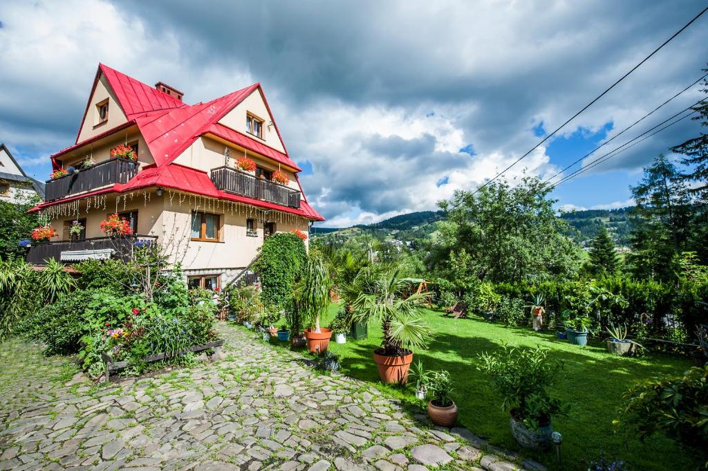 dom z czerwonym dachem z roślinami na dziedzińcu w obiekcie Apartament Klara w Zakopanem