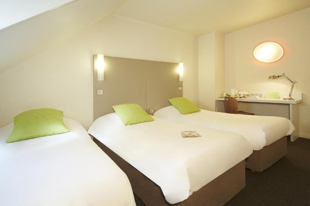 two beds in a hotel room with green pillows at Campanile Hotel Compiegne in Compiègne