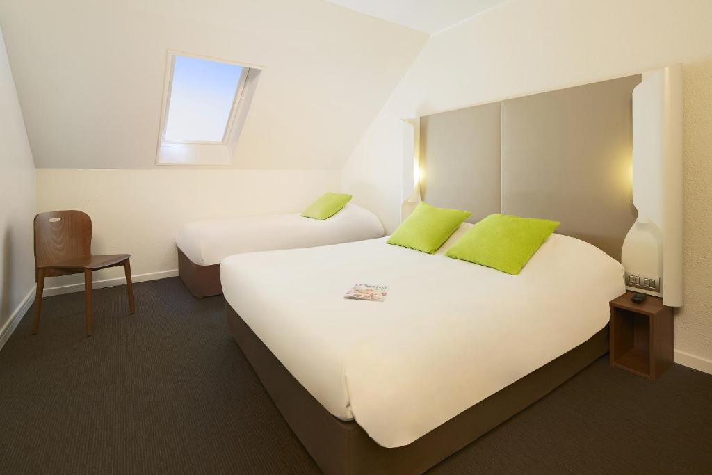 a hotel room with two beds and a chair at Campanile Hotel Compiegne in Compiègne