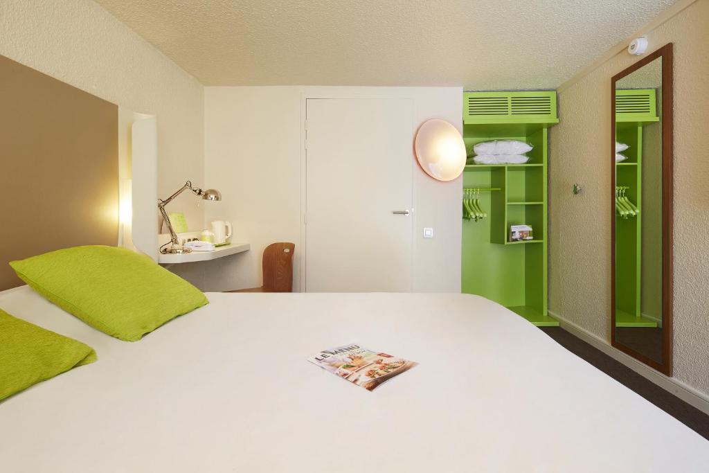 a bedroom with a white bed and a green door at Campanile Hotel Compiegne in Compiègne
