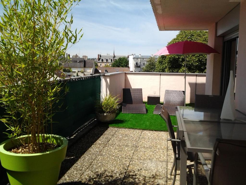 a balcony with a table and chairs and an umbrella at Les Burgondes in Dijon