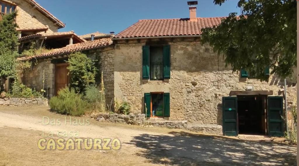 een oud stenen huis met groene luiken ervoor bij Casaturzo in Turzo