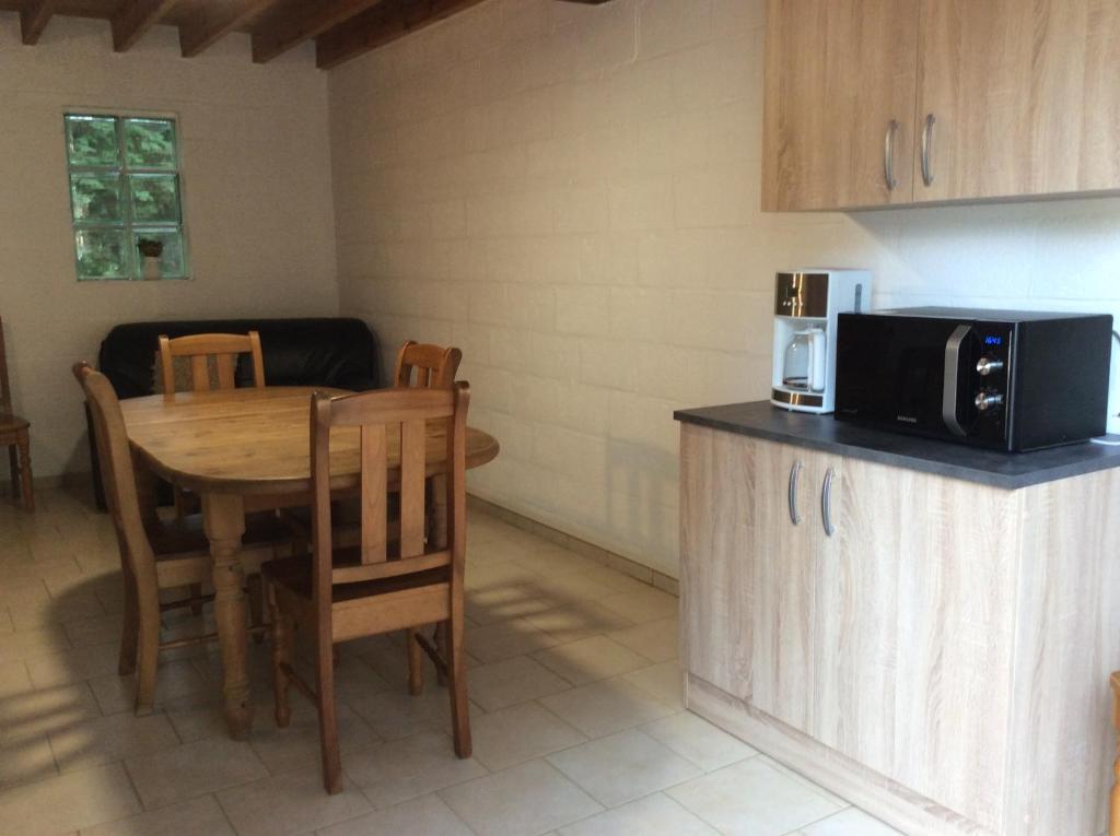 a kitchen with a table and a microwave at Le Domaine Appartements in Bilstain