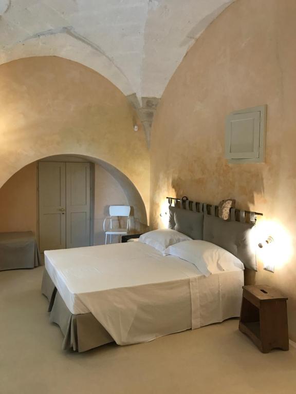 1 dormitorio con 1 cama blanca grande y 2 arcos en Tenuta Castelle, en Cutrofiano