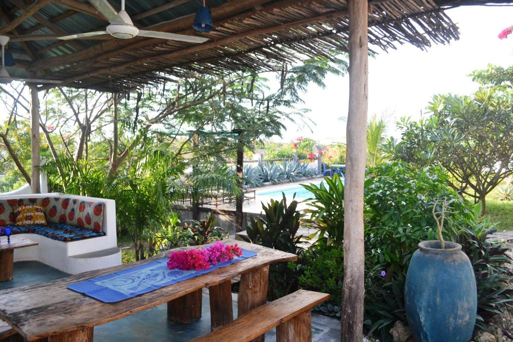 a patio with a bench and a table with flowers at Nakupenda Apartments in Kiwengwa