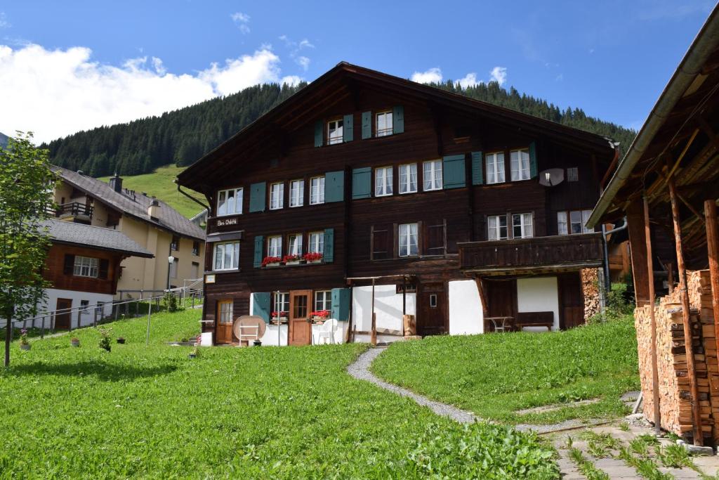 a large wooden house on a hill with green grass at Chalet Bim Chilchli in Mürren