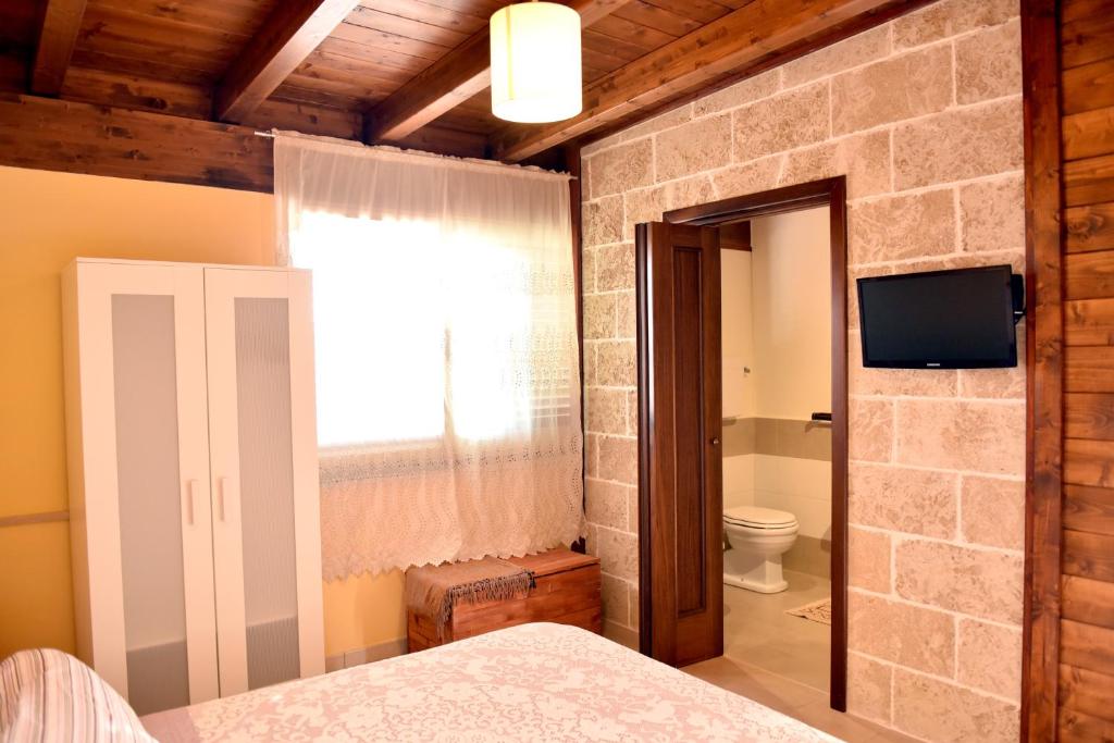 sypialnia z kamienną ścianą oraz łazienka z toaletą w obiekcie B&B Villa Anastasia Club w mieście Mesagne