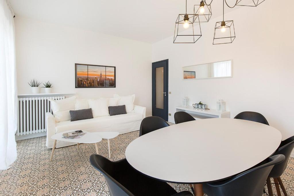 un soggiorno bianco con tavolo e sedie bianchi di La Promenade by Impero House a Stresa