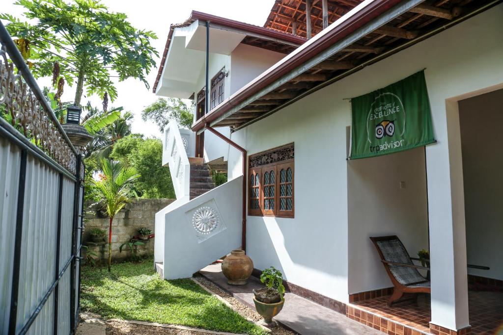a house with a green sign on the side of it at Ranjith Guest in Mirissa