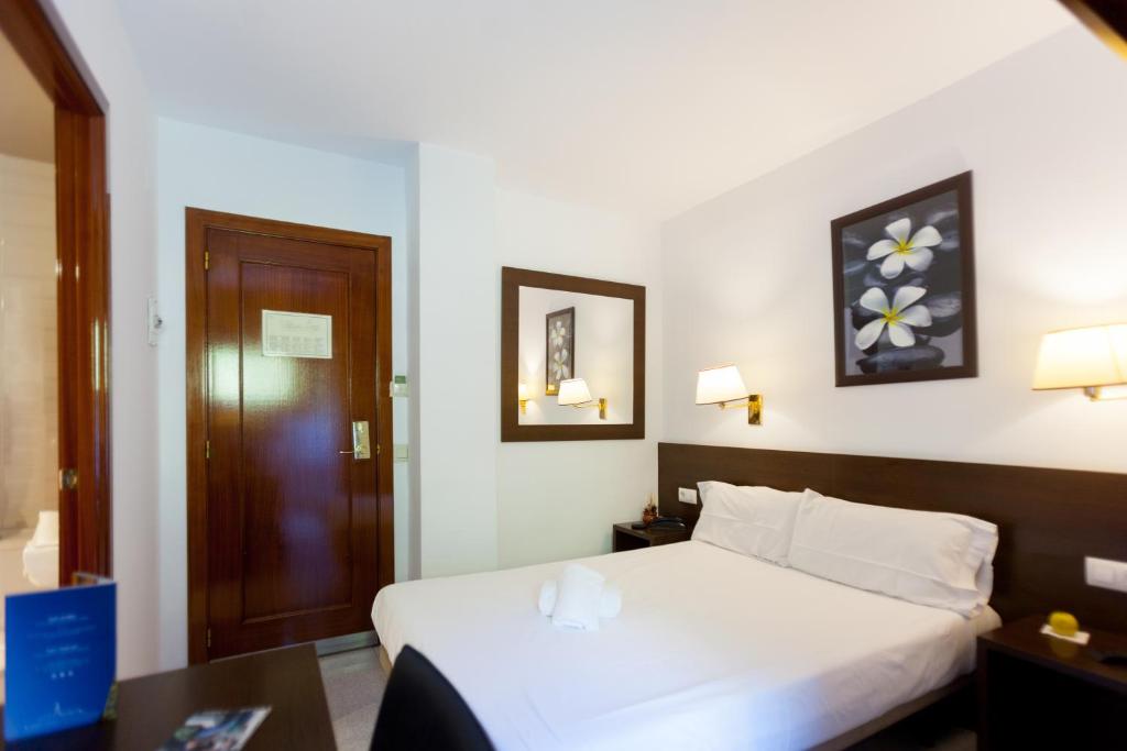 a bedroom with a white bed and a wooden door at Insitu Eurotel Andorra in Andorra la Vella