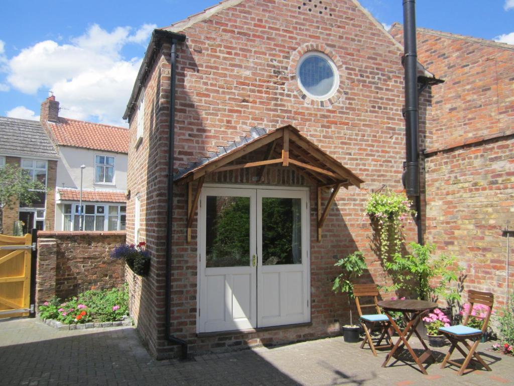 a brick church with a white door and a table and chairs at Carpenter's Cottage in Pocklington