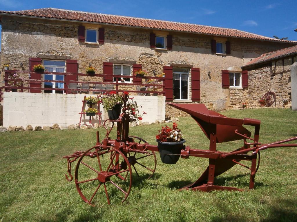 um tractor vermelho com flores num quintal em frente a um edifício em la chomiarde em Saint-Médard-de-Presque