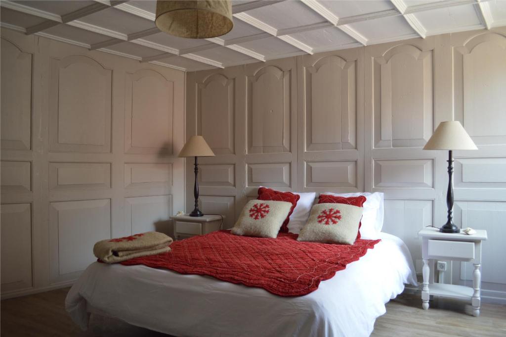 a bedroom with a bed with red and white pillows at Les Appartements De Louise in Riquewihr