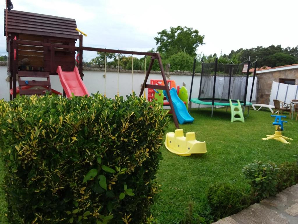 un patio trasero con un parque infantil con un columpio en Apartamentos Barrosa, en Portonovo