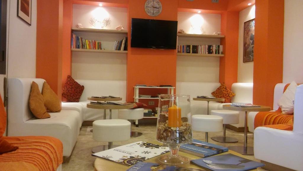 una sala de estar con paredes de color naranja y muebles blancos. en Albergo Rosa & Cosetta en Casal Borsetti
