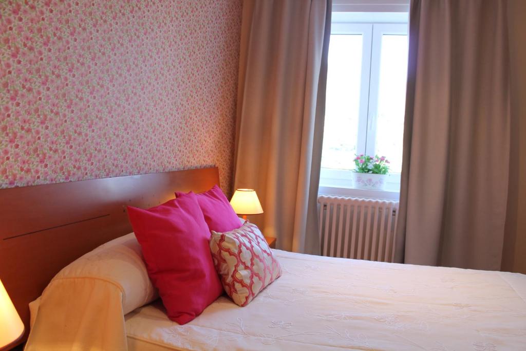 a bedroom with a bed with pink pillows and a window at Hotel Montero in Mondoñedo