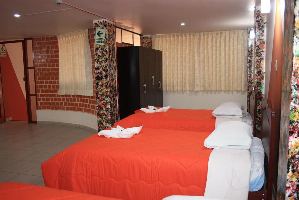 duas camas num quarto com lençóis vermelhos e cobertores brancos em Hotel Los Gladiolos em Cajamarca