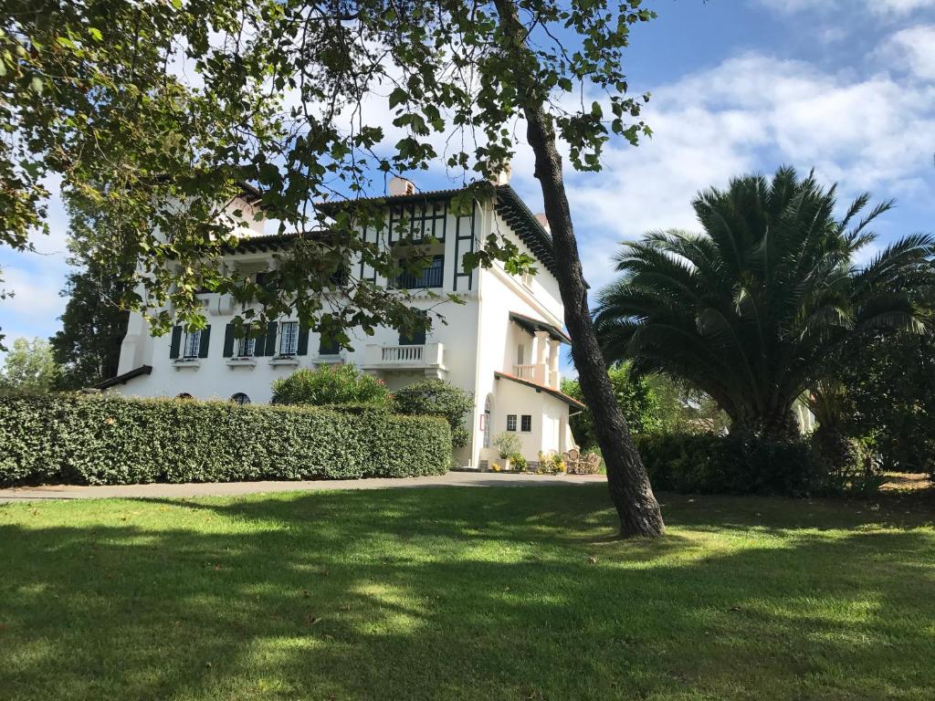 a white house with a tree in a yard at Domaine de Bordaberry in Urrugne