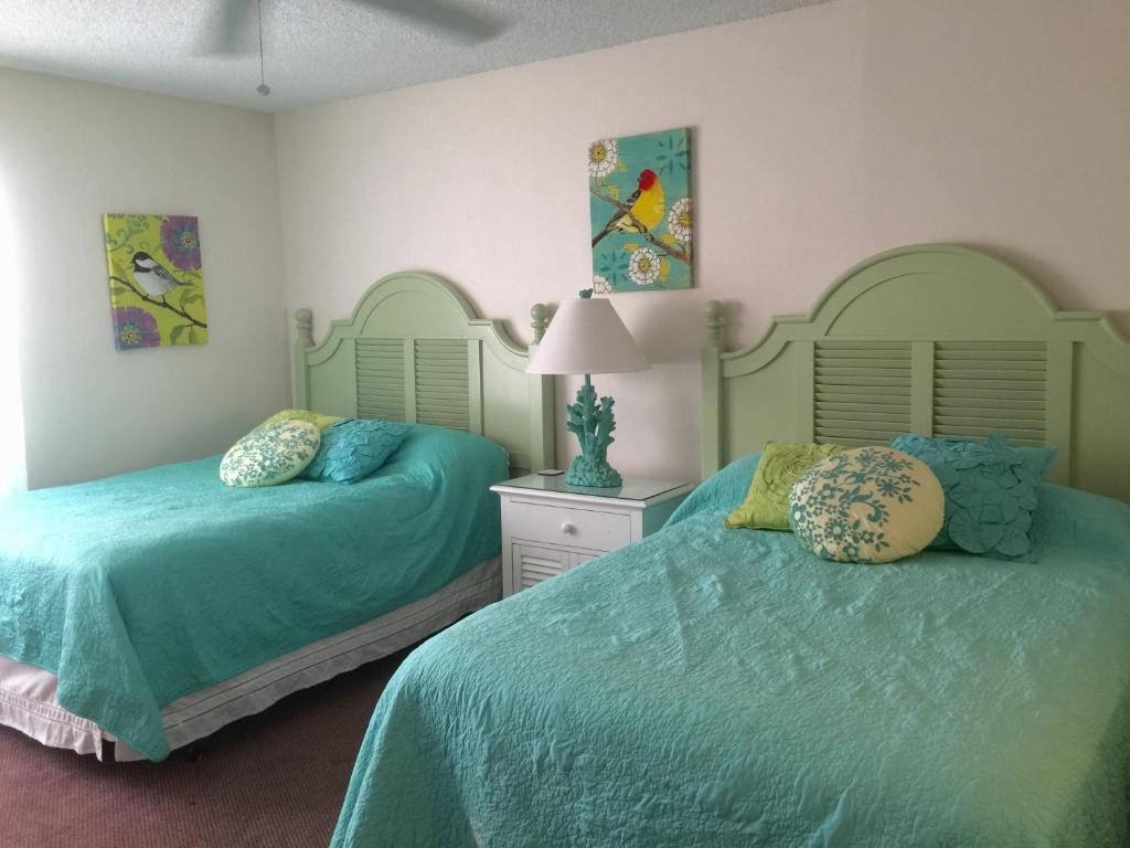 two beds in a bedroom with green sheets and pillows at Beautiful Ocean view Townhouse in Cocoa Beach