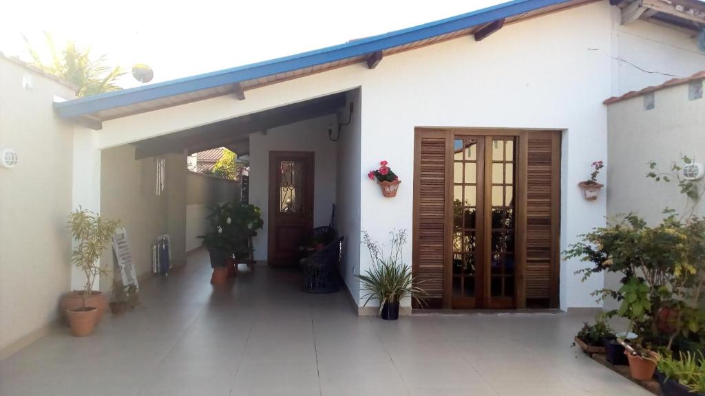 a white house with wooden doors and potted plants at Casa Centro De Ubatuba in Ubatuba