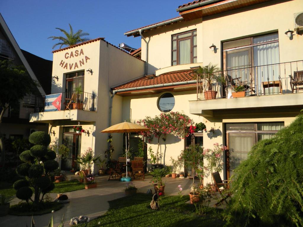 a large white building with plants and an umbrella at Casa Havana in Costinesti