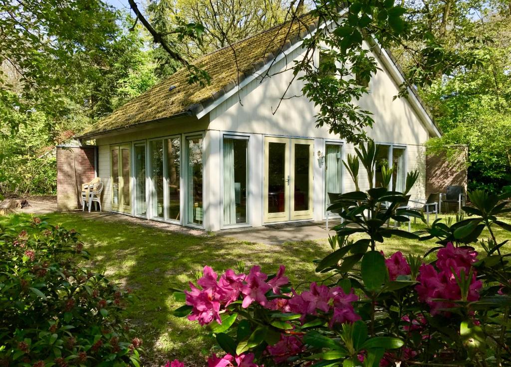 ein Haus mit Fenstern und Blumen im Hof in der Unterkunft Vakantiewoning Tjiftjaf in "Het Fonteinbos" in Oudemirdum