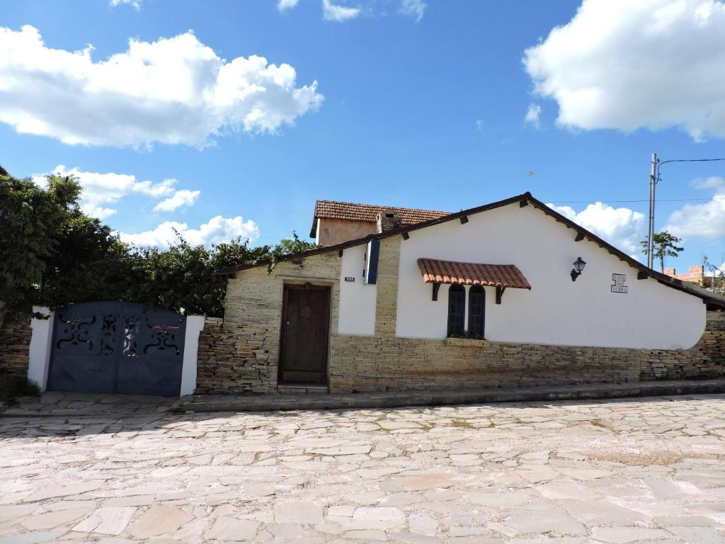 a small white house with a door and a stone driveway at Pousada Casa da Serra in São Thomé das Letras