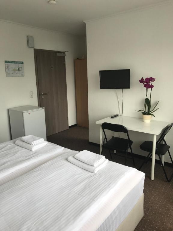 a hotel room with two beds and a desk with a computer at Hotel-Pension Alt-Heidenberg in Siegen