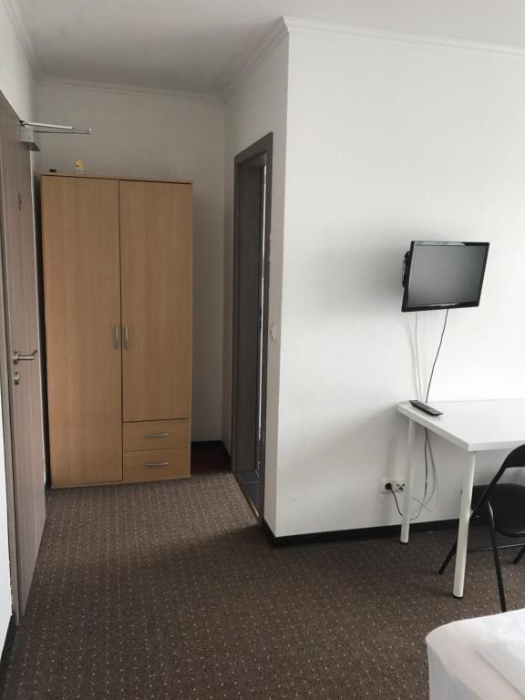 a room with a closet and a desk and a television at Hotel-Pension Alt-Heidenberg in Siegen